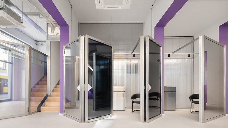 Moderne Büros mit transparenten Kabinen und einer Treppe, mit lila Akzenten. Moderne Büros mit transparenten Kabinen und einer Treppe, mit lila Akzenten.
