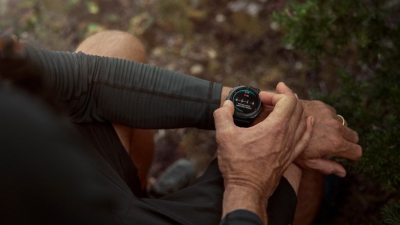 A person checking a Garmin smartwatch on their wrist in an outdoor setting. A person checking a Garmin smartwatch on their wrist in an outdoor setting.