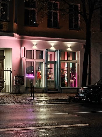 A brightly lit storefront at night featuring mannequins and colorful displays.