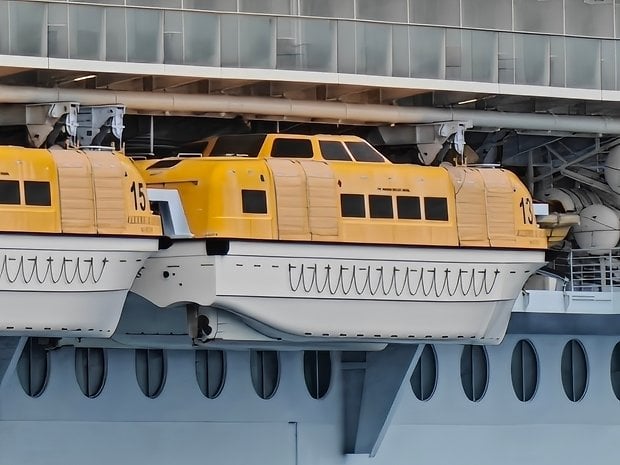 Dois botes salva-vidas amarelos encaixados na lateral de um navio.