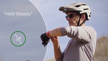 A cyclist wearing a helmet checks a smartwatch, with the text 'Hold Steady' and a satellite icon.