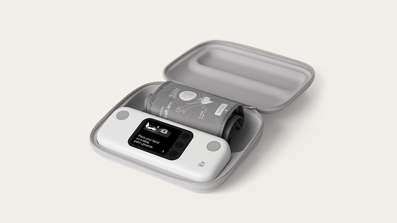 A blood pressure monitor in a gray carrying case with instructions displayed on the screen.