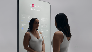 A woman interacts with the Withings OMNIA smart mirror displaying cardio analysis data.