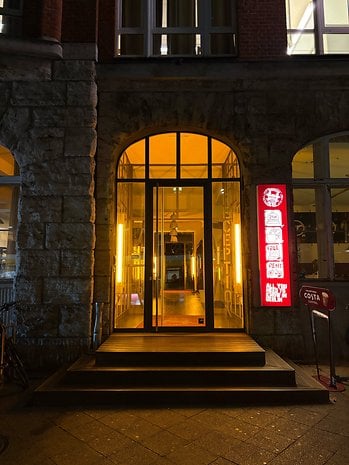Illuminated entrance of a building with a reception sign and a coffee shop sign nearby.