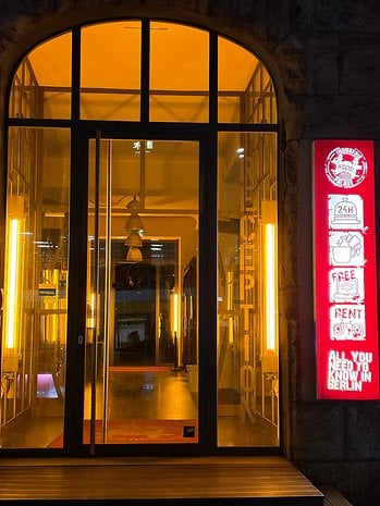 Entrance of a hostel with illuminated signs and a welcoming atmosphere.