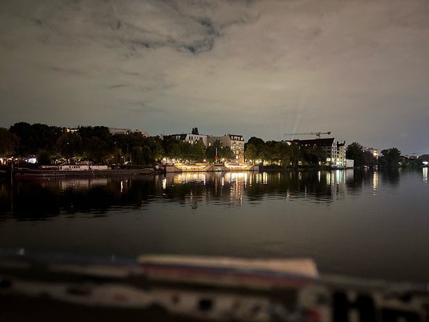A serene night scene of a river with illuminated buildings reflecting on the water.