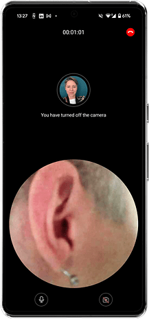 Une interface d'appel vidéo montrant un gros plan sur une oreille et le visage d'une personne dans un cadre circulaire.