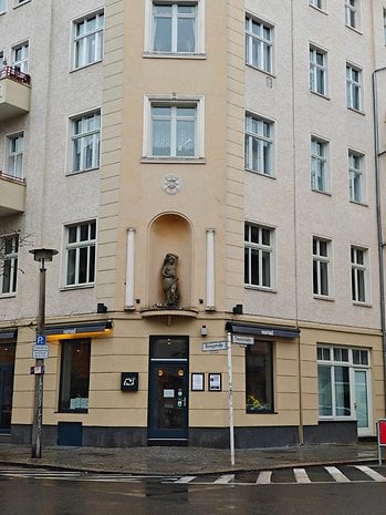 A building corner with an ornate statue, large windows, and a sign for 'nomad' cafe.