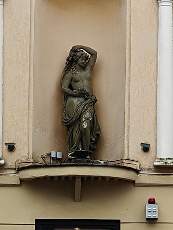 A statue of a woman holding flowers on a building facade.