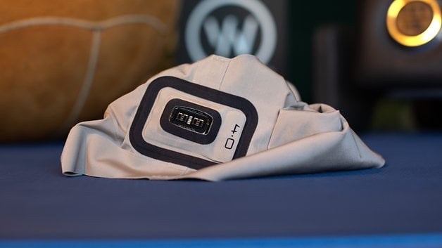 A Whoop MG sensor on a folded piece of fabric, set on a blue surface with a blurred background.
