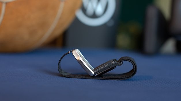 A Whoop MG sensor lying on a blue surface with a blurred background, showcasing its design.