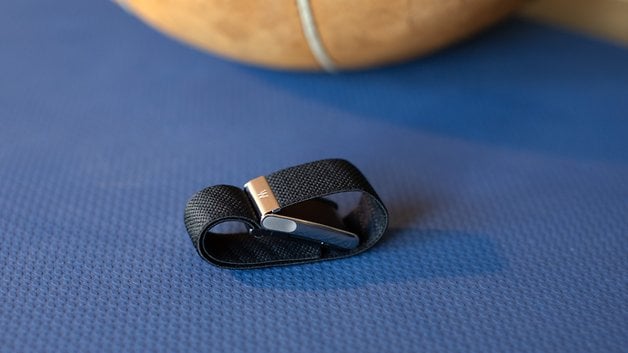 A Whoop MG sensor strap resting on a blue surface, with a basketball partially visible in the background.