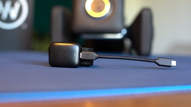 A Whoop MG sensor connected with a black USB cable, placed on a blue mat.