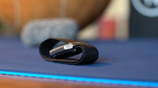 A Whoop MG sensor device lying on a blue mat, with a blurred background.