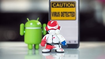 An Android figure and a malware character stand in front of a sign that says "Caution: Virus Detected."