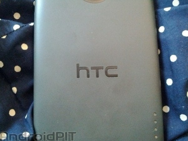 Logo HTC sur le dos d'un appareil sur un tissu à pois blancs sur fond bleu.