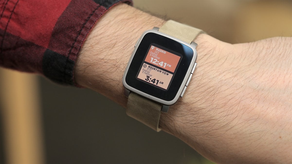 Un poignet portant une montre intelligente Pebble Time affichant l'heure et le lieu.
