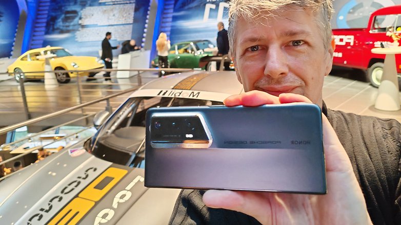 MaTT hält das Honor Magic V2 RSR im Porsche Design im Porsche Experince Center in die Kamera.