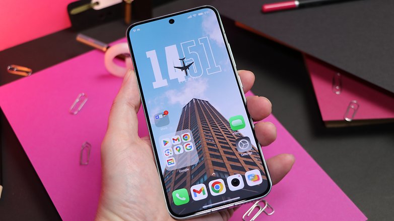 Le Xiaomi 14 vu de face, tenu dans une main gauche avec son écran d'accueil allumé