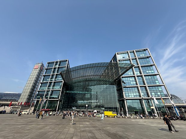 Estação Central de Berlim com arquitetura de vidro e pessoas na praça.