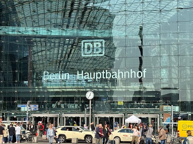 Berlin Hauptbahnhof mit einer Uhr und Menschen davor, mit Glas- und Metallarchitektur.