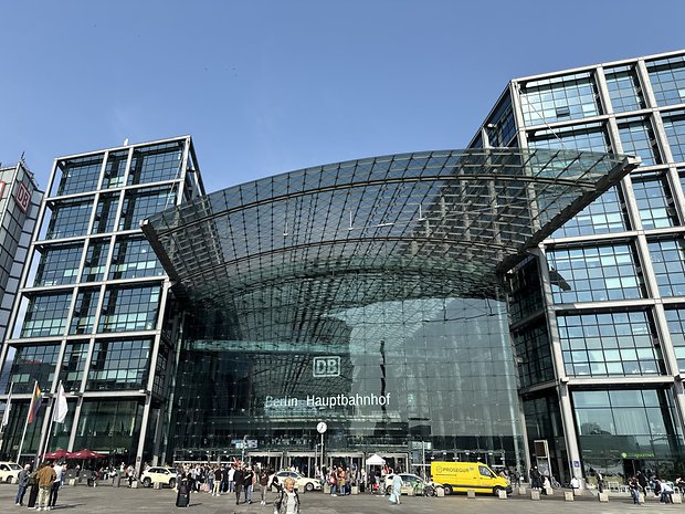 The Berlin Central Station in glass with people gathered outside.