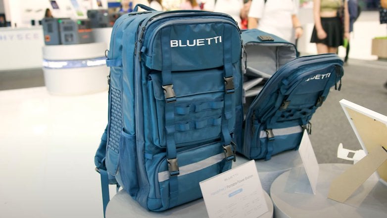 Ein blauer Bluetti-Rucksack, der mit einer Vorderansicht und einem offenen Innenraum auf einem Tisch ausgestellt ist.