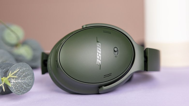 Le casque Bose QuietComfort Headphones vu de côté avec un zoom sur son oreillette droite et son bouton d'appairage