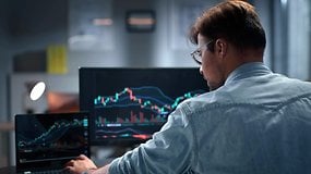Person sitting at a computer showing stock prices