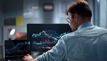 Person sitting at a computer showing stock prices