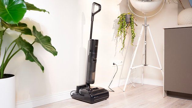 Ein Dreame H15 Pro Staubsauger steht neben einer Topfpflanze in einem modernen Interieur.