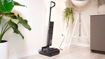 Ein Dreame H15 Pro Staubsauger steht neben einer Topfpflanze in einem modernen Interieur.