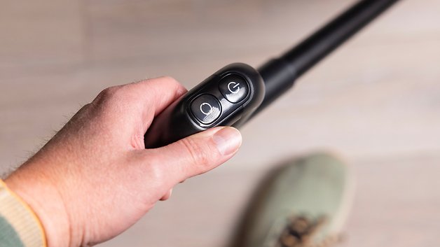 Eine Hand hält einen Steuergriff mit zwei Tasten für das Dreame H15 Pro Gerät.