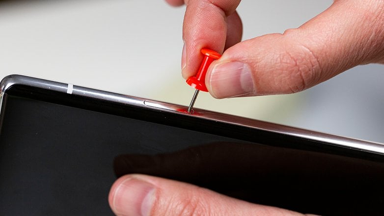 A person opening a SIM tray with a needle