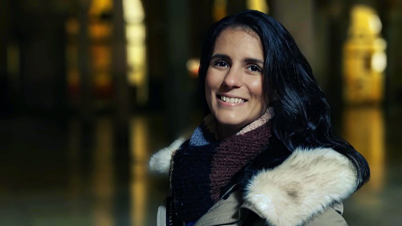 A woman smiling in night photography, with soft lighting and a blurred background.