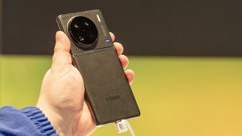 Le Vivo X90 Pro tenu par le testeur dans sa main gauche et vu de profil (de droite)