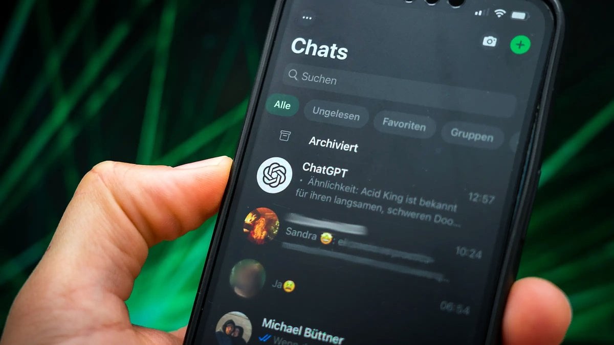 Une main tenant un smartphone affichant un chat WhatsApp avec 'ChatGPT' et d'autres contacts.