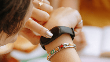 A person checking a black fitness tracker on their wrist.