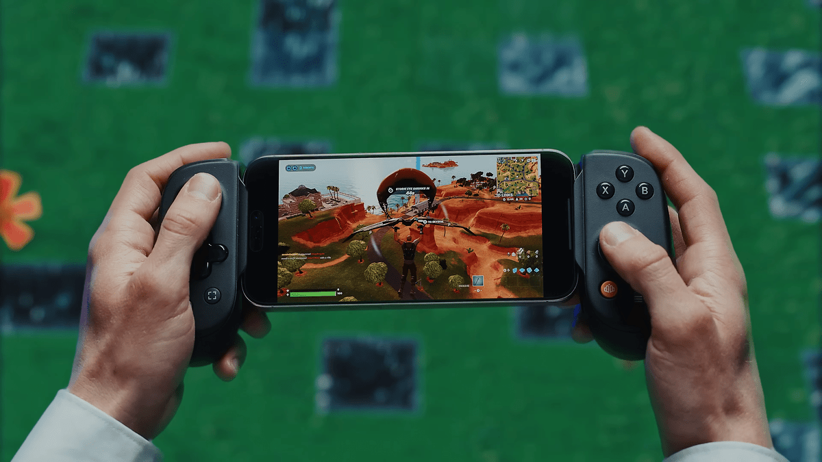 Une personne tient un contrôleur Backbone avec un smartphone affichant un jeu vidéo.