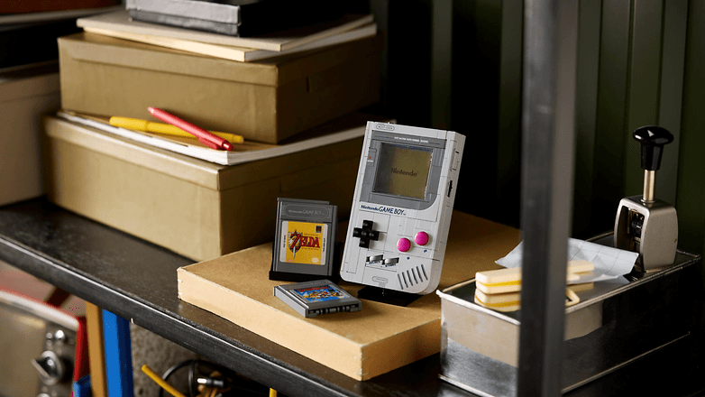 Ein vintage Game Boy mit Spielkassetten auf einem überfüllten Regal zwischen Kisten und Schreibwaren. Ein vintage Game Boy mit Spielkassetten auf einem überfüllten Regal zwischen Kisten und Schreibwaren.