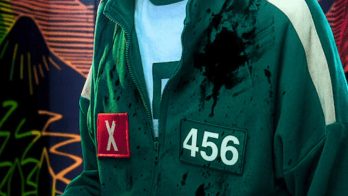 Une personne portant un survêtement vert avec le numéro 456 et un badge rouge 'X', taché d'éclaboussures.