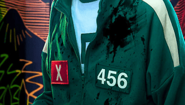 Une personne portant un survêtement vert avec le numéro 456 et un badge rouge 'X', taché d'éclaboussures.