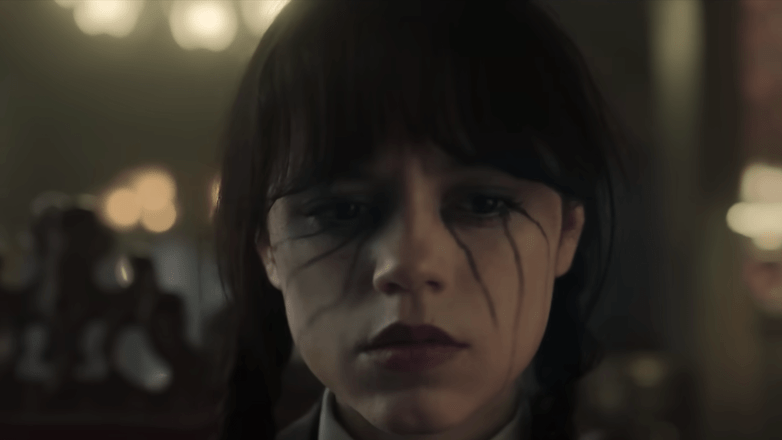 A close-up of a girl with dark makeup and braids, looking somber. A close-up of a girl with dark makeup and braids, looking somber.