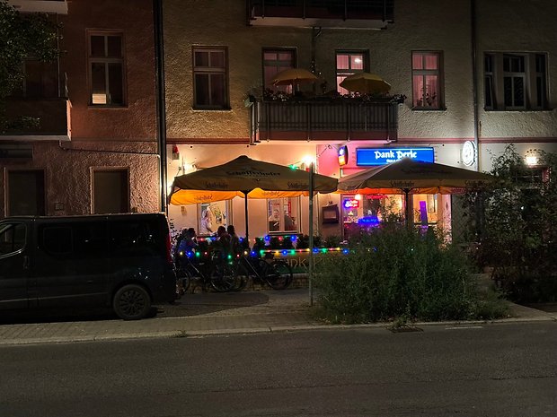 Photo prise avec l'iPhone 15 Pro Max de nuit de la terrasse d'un bar éclairée par une guirlande multicolore