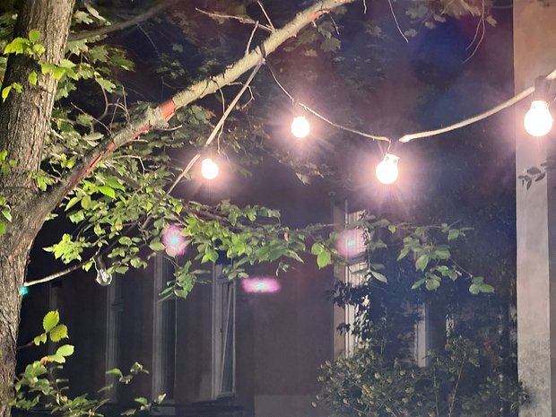 Photo prise avec l'iPhone 15 Pro Max de nuit d'une rue éclairée par une guirlande accrochée à des arbres