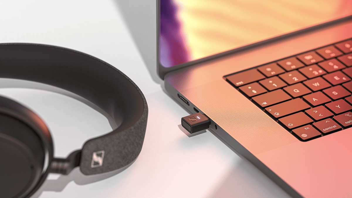 Adaptateur USB Bluetooth Sennheiser BTD 700 à côté des écouteurs et d'un ordinateur portable.