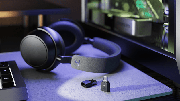 Casque Sennheiser BTD 700 à côté d'un dongle USB sur un bureau avec un clavier.