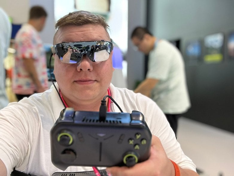 Person mit VR-Brille hält ein Spielgerät auf einer Tech-Veranstaltung.