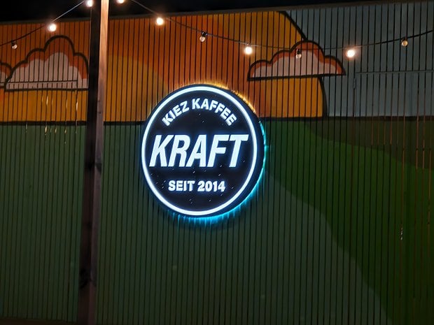 Un enseigne néon avec 'KIEZ KAFFEE KRAFT SEIT 2014' sur un mur coloré.