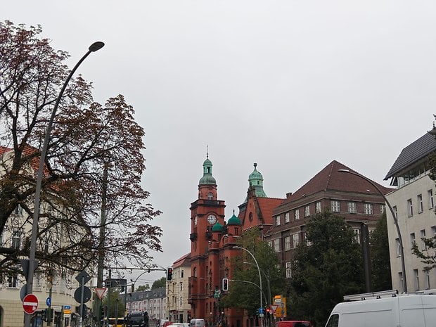 Vue de la rue avec des bâtiments historiques à dômes verts sous un ciel nuageux.